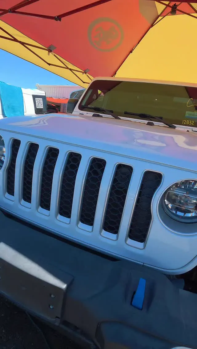 Detailed white Jeep grille and headlamp beneath a detailing canopy.
